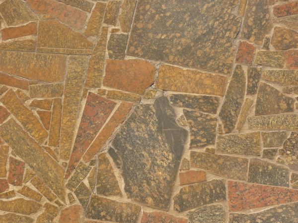 Pavement consisting of stone slate cut in pieces of random shapes and set in brown cement.
