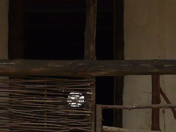 Small, old village house with two storeys made of wood and clay. Roof consists of thatched hay.