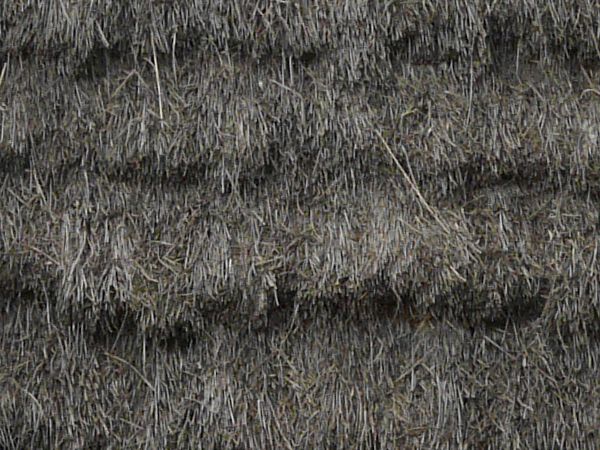 Small cabin made of large, wooden logs with tall, thatched roof.