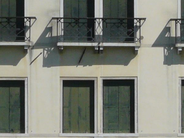 Large, multi-storey building with slightly worn, white surface standing on water.