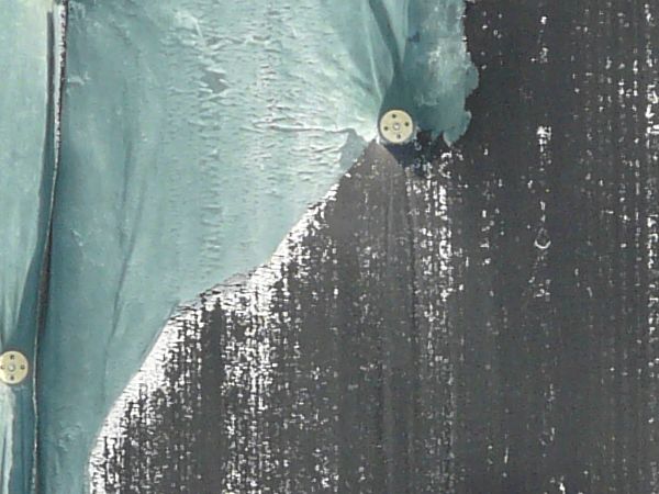 Wall texture, covered by pieces of thin green plastic divided by thin white strips. A worn black surface is visible behind some of the plastic.