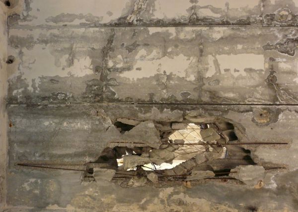 Large, rectangular blocks of concrete with irregular surface and large hole exposing metal armature.