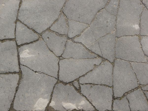 Texture of concrete in grey tone with cracked surface and dirt in cracks.