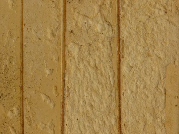 Old foam paneling in yellow tone with worn, damaged surface.