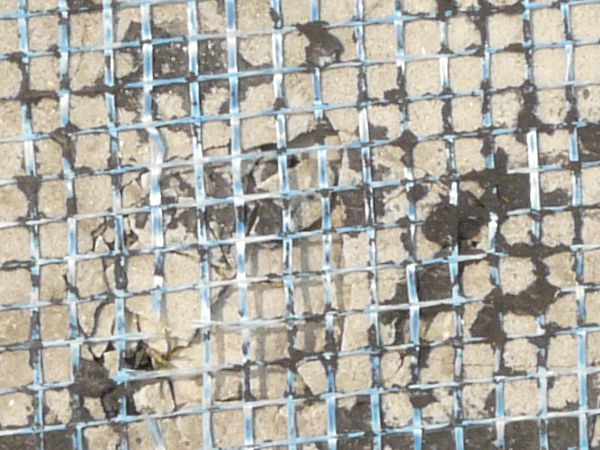Plastic mesh texture embedded in dirty rubber and plaster.