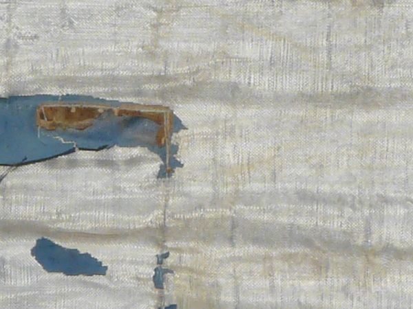 Texture of tall fence with worn, torn plastic covering on bottom.