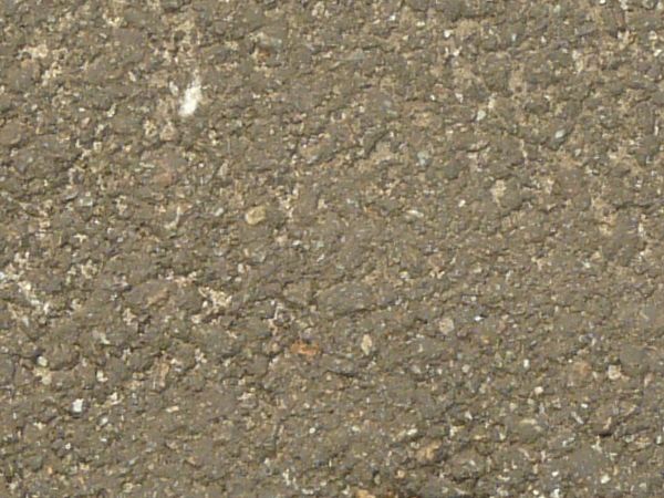Road texture with dark areas of asphalt patching holes, thin crack extending from the patches, and a small, unfilled hole.