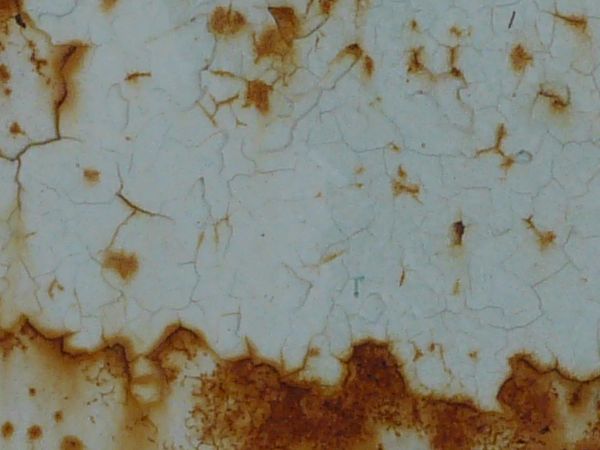 Brown rust scratches and stains texture, visible on a surface of cracking white paint.