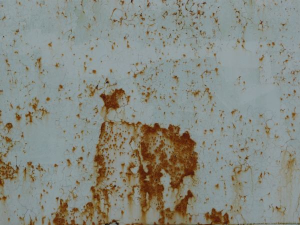 Brown rust scratches and stains texture, visible on a surface of cracking white paint.