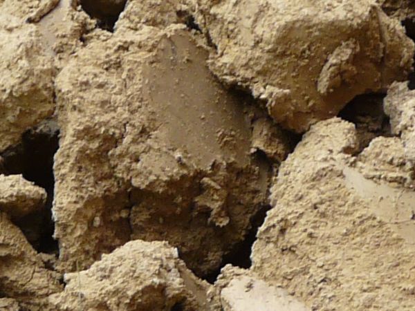 Brown soil texture, dried into large, rough-edged chunks.