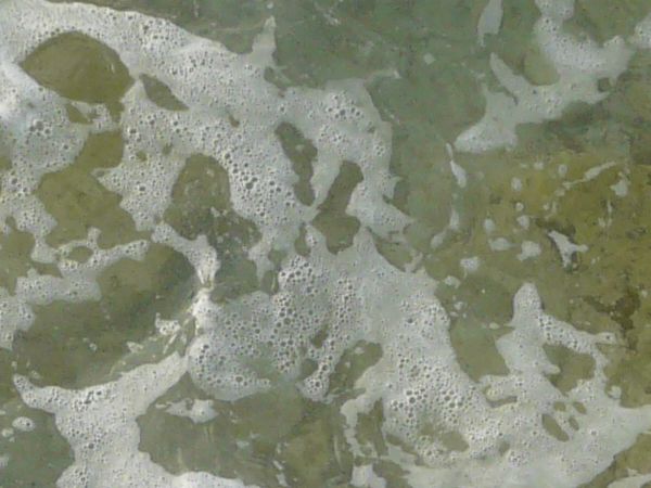 Water texture with slightly murky consistency and large, brown rocks below surface.