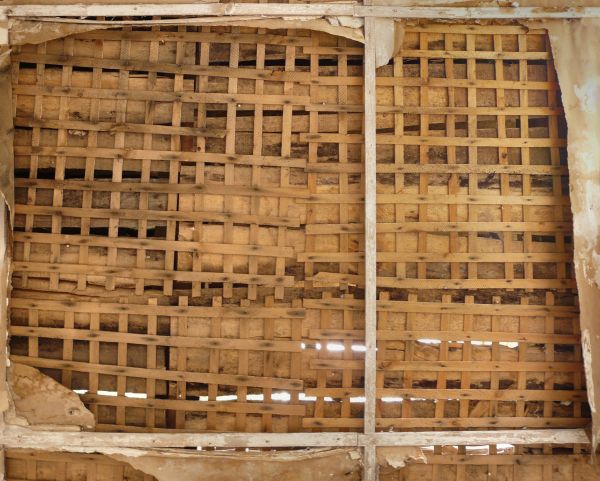 Wall made of thin wooden planks set in repeating, gridded pattern with slightly worn surface.