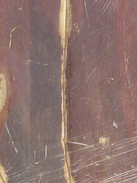 Damaged red wood texture with three large holes and long, light brown cracks.